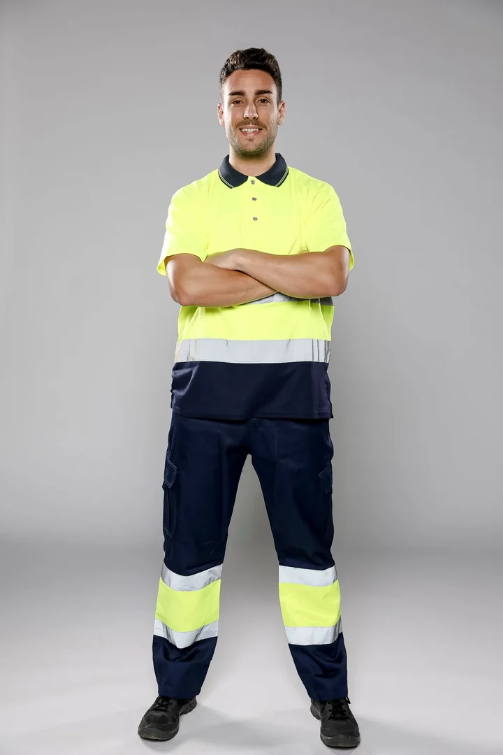 Man in a yellow and navy hi-vis polo shirt and navy work trousers with reflective stripes
