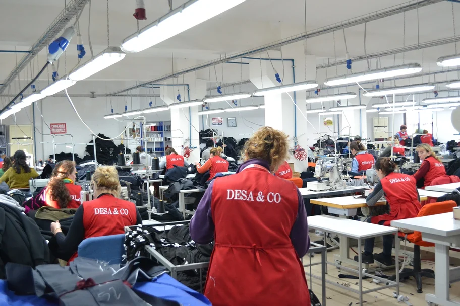 Sewing floor of the Desa & Co clothing factory in Tirana, with machinists in red Desa & Co aprons
