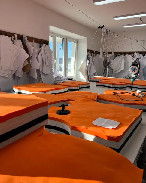 Cutting room with stacks of cut fabric panels and paper patterns hanging on the wall